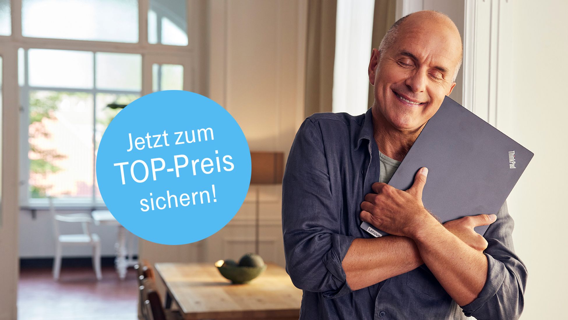 Comedian Christoph Maria Herbst hält lächelnd einen Laptop im Arm
